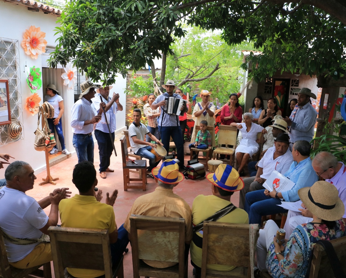 Parranda vallenata en patio con acordeón, caja y guacharaca rodeados de público
